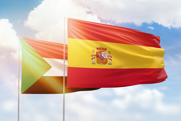 Sunny blue sky and flags of spain and sudan