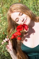 Young lovely romantic woman with a bouquet of poppies on the field. Summertime background.