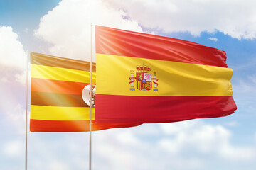 Sunny blue sky and flags of spain and uganda