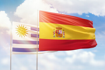 Sunny blue sky and flags of spain and uruguay