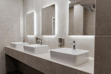 Fototapeta na wymiar modern bathroom with three vessel sinks and illuminated mirrors