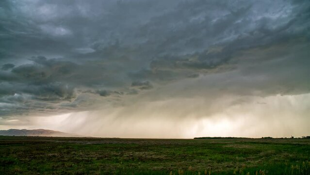 Rain storm moving over the marsh on Utah Lake through the valley following dramatic clouds rolling in the sky.