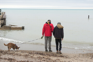 Father and special needs son walking on the beach with their dog; outdoor family fun