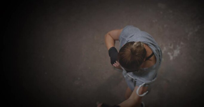 Cinematic shot of Professional female boxer practising shadow boxing in cross training workout space. Young asian woman fighter exercising in abandoned building dark hall gym. working out on her moves