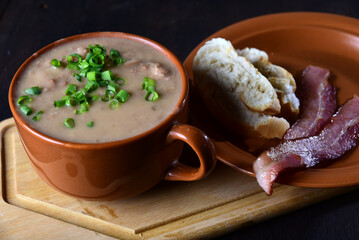 bean broth with herbs bread and bacon in a porcelain bowl, typical brazilian food, bean soup