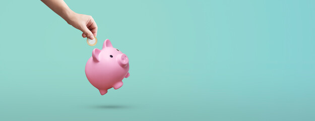 man depositing a coin in a pink piggy bank on a blue background - savings concept