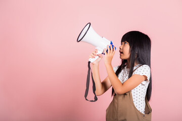 Asian little kid 10 years old shouting by megaphone at studio shot isolated on pink background, Happy child girl lifestyle she screeching through in megaphone announces discounts