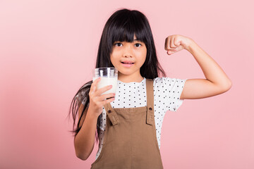 Asian little kid 10 years old smile holding milk glass and show power strong gesture at studio shot...