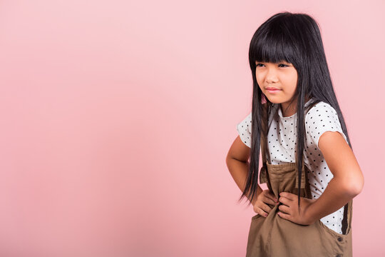 Asian Little Kid 10 Years Old Suffering From Stomach Ache At Studio Shot Isolated On Pink Background, Happy Child Girl Hand Hold Stomach Pain Because Indigestion, Painful Illness Feeling Unwell