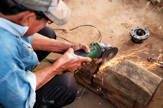 Male worker cutting metal iron with angle saw with sparks.