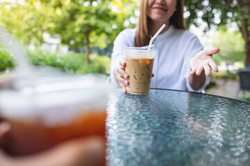 Closeup image of a couple people talking and drinking coffee together in the outdoors