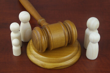 Family law concept. Judge gavel with many wooden figures of family members close-up.	
