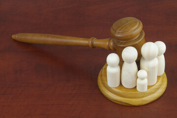Family law concept. Judge gavel with many wooden figures of family members close-up.	