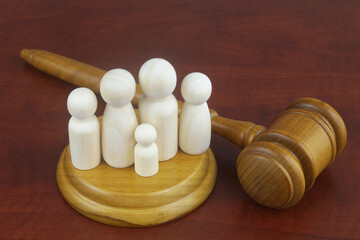 Family law concept. Judge gavel with many wooden figures of family members close-up.	