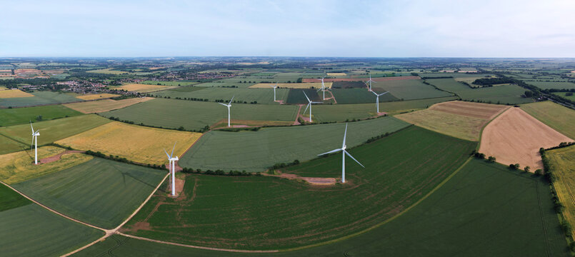 Panoramic Aerial View Of Green Energy Generator Wind Turbines Farms, Solar At Village Of England UK
