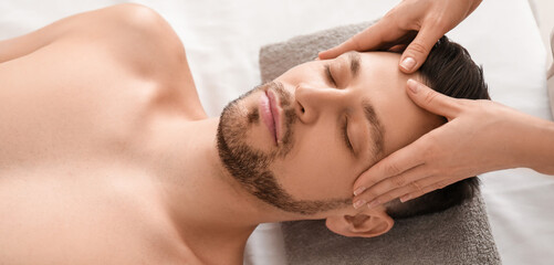 Handsome man having face massage in spa salon