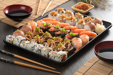 Japanese food combo and crispy onions served in restaurant on black plate on wooden table