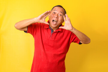 Asian senior man wearing casual t shirt isolated yellow background shouting and screaming loud with hand on mouth. Communication concept.