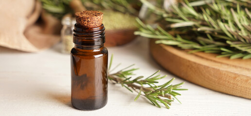 Bottle of healthy rosemary essential oil on light background