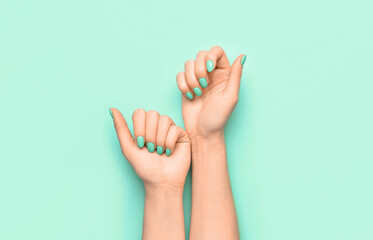 Female hands with beautiful manicure on mint background