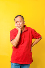 Asian senior man suffers from toothache isolated on yellow background. 