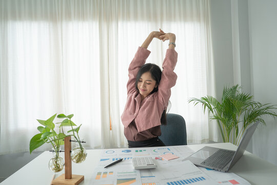 Businesses or working lady is stretch themselves or lazily for relaxing on their desk while doing their work in the office.