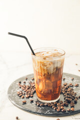 Board with glass of cold brew and coffee beans on white table