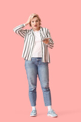 Naklejka premium Shocked blonde woman with calculator on pink background
