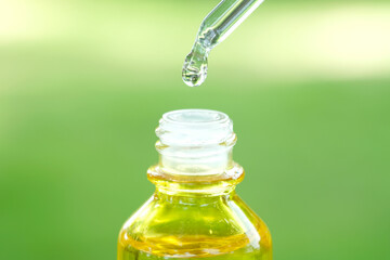 Dropping serum collagen moisturizer of face into clear yellow bottle soft light background. Protector skin Treatment facial essence oil, Vitamin C. Beauty and spa Concept.