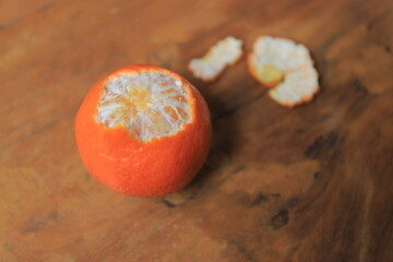 Fresh orange, partially peeled, on a wooden table