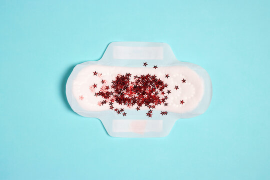 Menstrual pad with red glitter stars on blue background