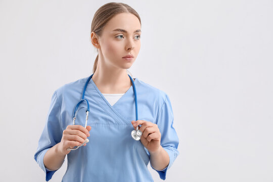Female nurse with stethoscope on light background