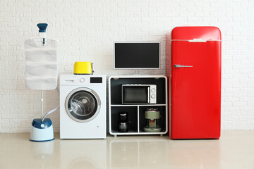 Modern household appliances near white brick wall in room