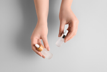 Female hands with bottles of serum on white background, closeup