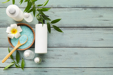 Bottles of natural serum, bowl with salt and plant leaves on green wooden background