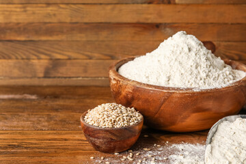 Scoop and bowls with wheat flour on wooden background