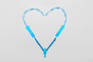 Fototapeta na wymiar Heart made of blue paper clips, sticky notes and compasses on light background