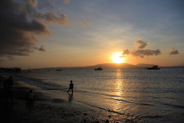 Beautiful view of sunrise on the beach with silhouettes people on the waterfront. Great for Background. 
