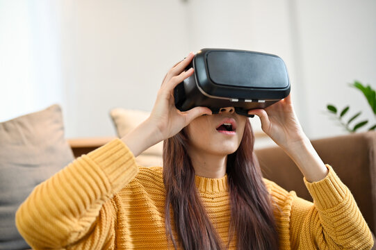 Amazed and excited young asian woman watching the movie via VR headset