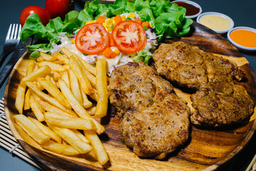 Grilled steak and lettuce, French fries on wooden plate