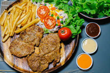 Grilled steak and lettuce, French fries on wooden plate