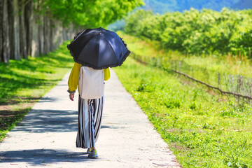 黒い日傘をさして歩く女性