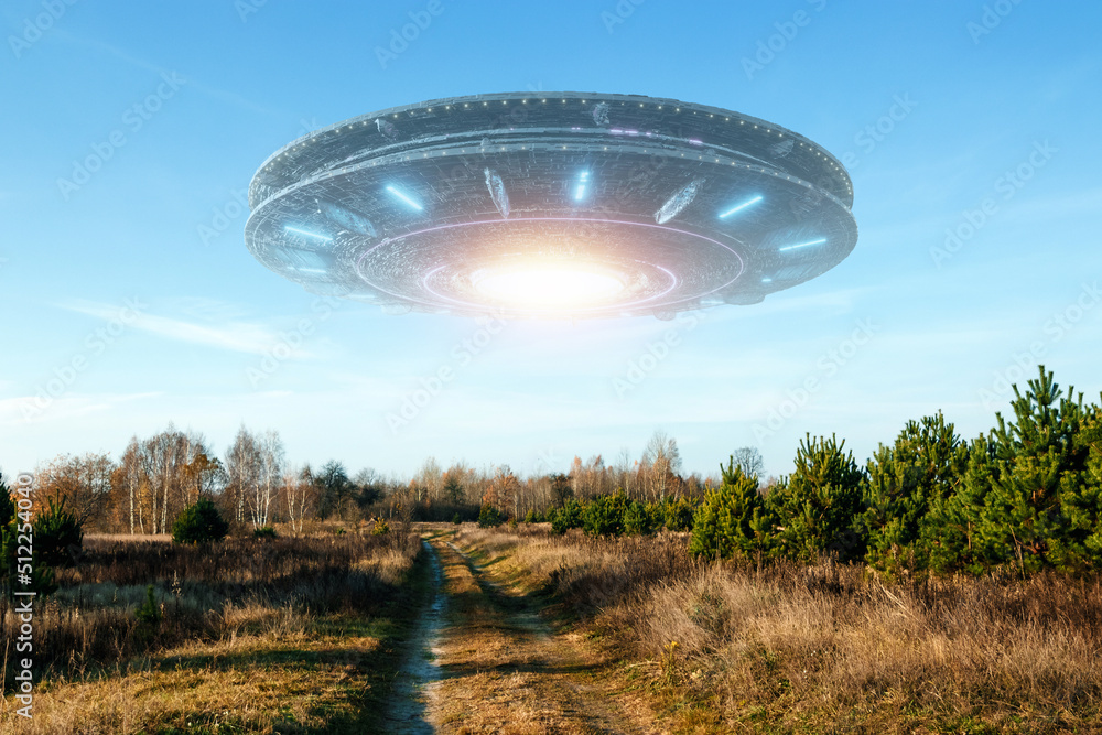 Wall mural ufo, an alien saucer hovering above the field in the clouds, hovering motionless in the sky. unident