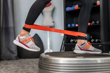 Feet of unknown woman and rubber elastic resistance band while standing on power plate vibration platform machine during training workout exercise copy space - obrazy, fototapety, plakaty