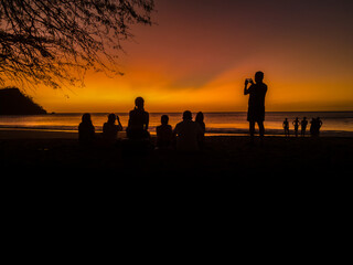 View of a magical sunset on the beach  with silhouette of peolple enjoying in the beach of Costa Rica