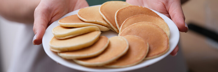 Flour sweet pancakes on white plate in female hands closeup