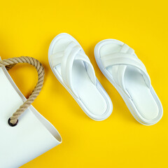 Women's summer white slippers and a white rubber bag with brown handles on a yellow background. Slippers. Square image