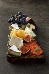 Wooden plate with cheese, fruits and sausages. Snacks on plate