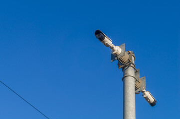 CCTV cameras on the post of the railway station against the background of the blue sky. Means of video surveillance and security. Selective focus