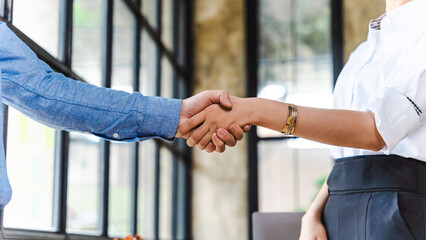 Team of Asian businessmen and women shake hands together to create a mutually beneficial business...